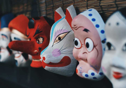 A photograph of a number of painted porcelain masks on a shelf