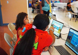 Two children study language materials on a computer