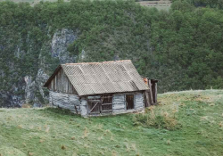 A photograph of an old house on a grassy hilltop