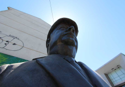 A photograph of a statue taken from down low with the sun's halo encircling the head