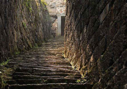 Steps, roughly cut from stone, leading steeply toward a door, partially obscured by the curvature of the rock