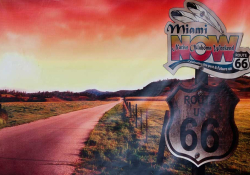 A color-altered photograph (emphasizing red tones) of a highway with a sign beside it in the foreground. The sign reads Route US 66. Another sign has been placed above it that read Miami Now, Native Oklahoma Weekend. Celebrating the past and future on Route 66.