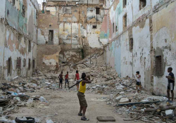 A group of boys play stickball in an urban cul-de-sac filling up with piles of rubble