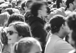 A black and white photo of a crowd with a figure at its center who is blurred