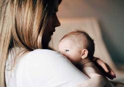 A photograph of a woman holding a baby. Her face is in shadow