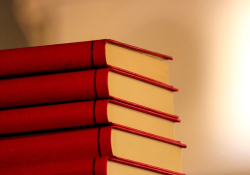 A stack of five red books with a warm glow around it