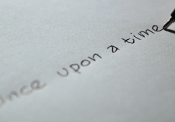 The words "Once upon a time" written on a piece of paper with a ink pen resting but poised to continue on the final stroke