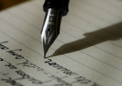 An old-style fountain pen writes on lined paper.