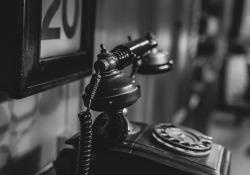 A black and white photo of a vintage phone in a study