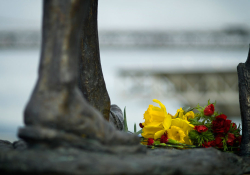 A close-up of a human foot in statue form with flowers laid before it