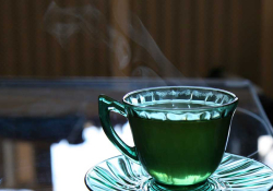 A photograph of a cup of tea. The cup is clear and the tea is green