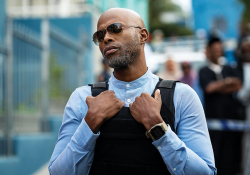 A man dressed in a police uniform grips the edges of his bullet-proof vest as he looks of in the distance