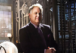 A man in a suit stands in front of an antique style open elevator