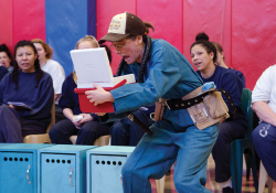 Spectators watch as an actor in costume peers inside of a mini-cooler