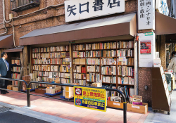 A Japanese salaryman pauses at a bookstall on the corner of two intersecting streets